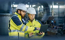 people in ppe looking at a laptop in an industrial setting