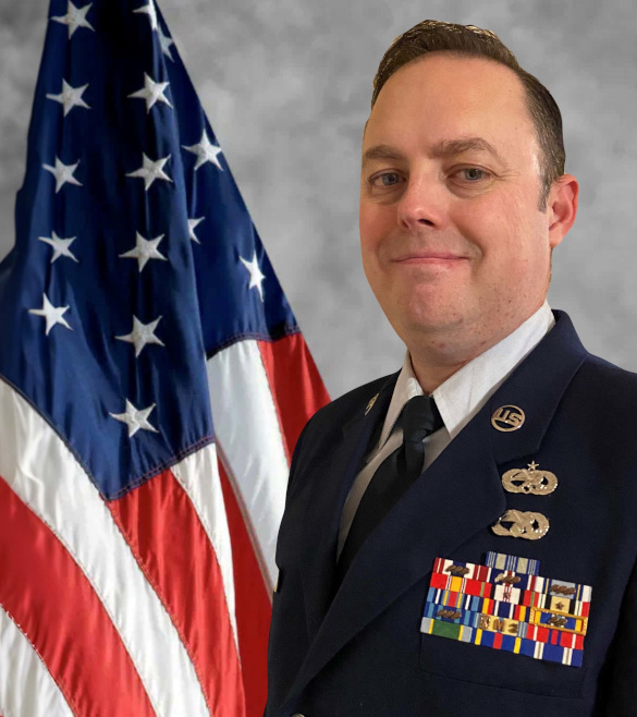 Justin Wise formal portrait in full uniform standing next to the American flag.