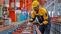 Manufacturing Quality Inspection and Process Monitoring Worker inspecting production equipment in a manufacturing facility.