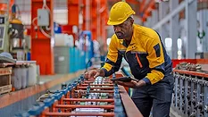 Worker inspecting production equipment in a manufacturing facility.