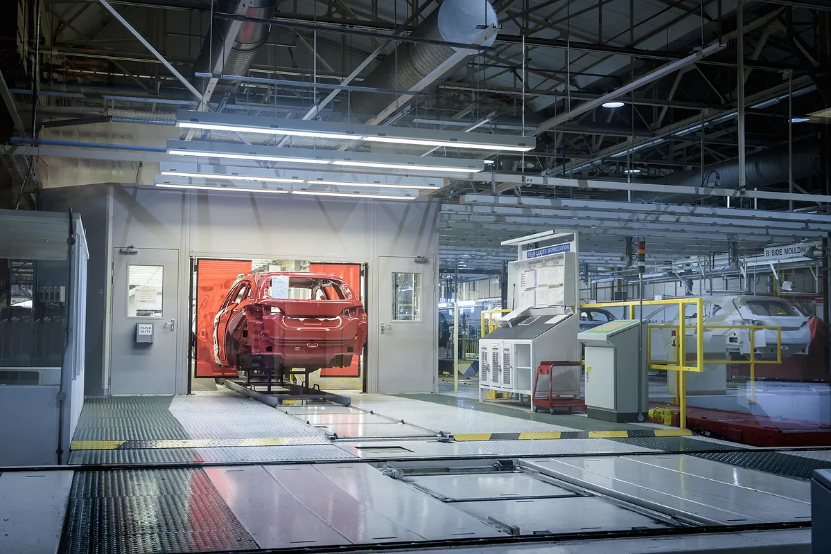 Vehicle body moving through an automotive assembly line in a manufacturing plant.