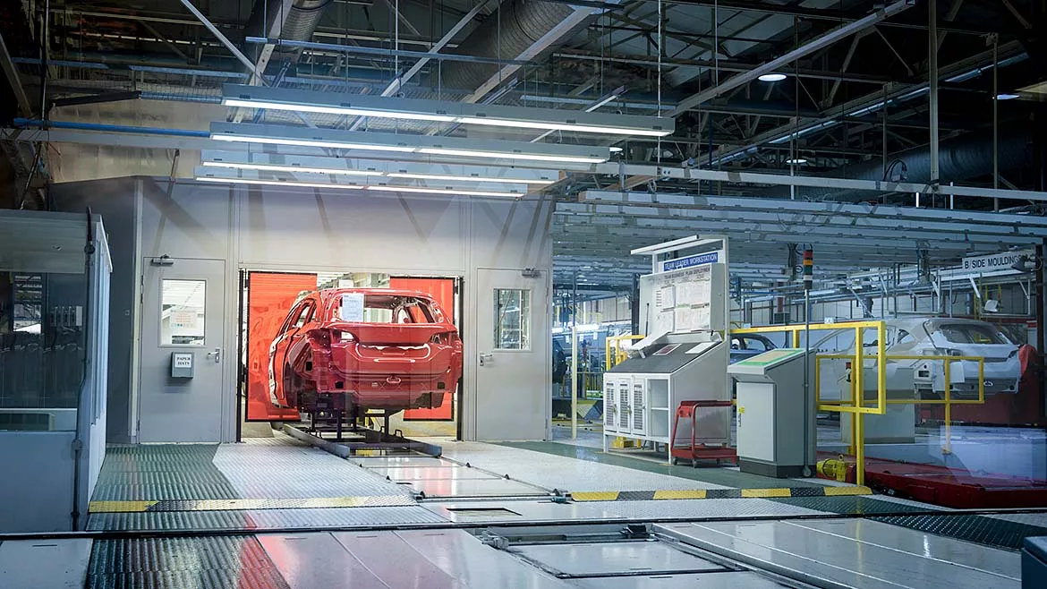 Vehicle body moving through an automotive assembly line in a manufacturing plant.