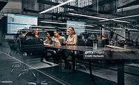 Business professionals collaborating in a modern conference room, reviewing data and discussing strategy using tablets and digital dashboards.