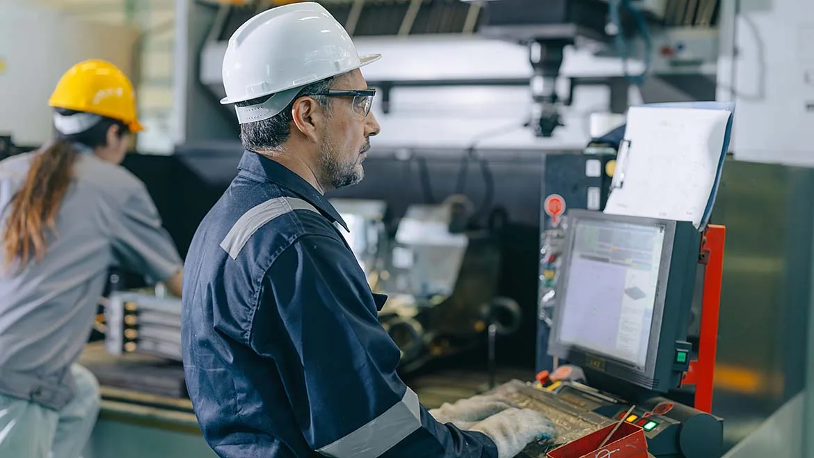 CNC operator monitoring a machining center control panel.