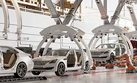Automated automotive assembly line with robotic systems and vehicle bodies moving through a modern car manufacturing facility.
