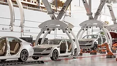 Automated automotive assembly line with robotic systems and vehicle bodies moving through a modern car manufacturing facility.
