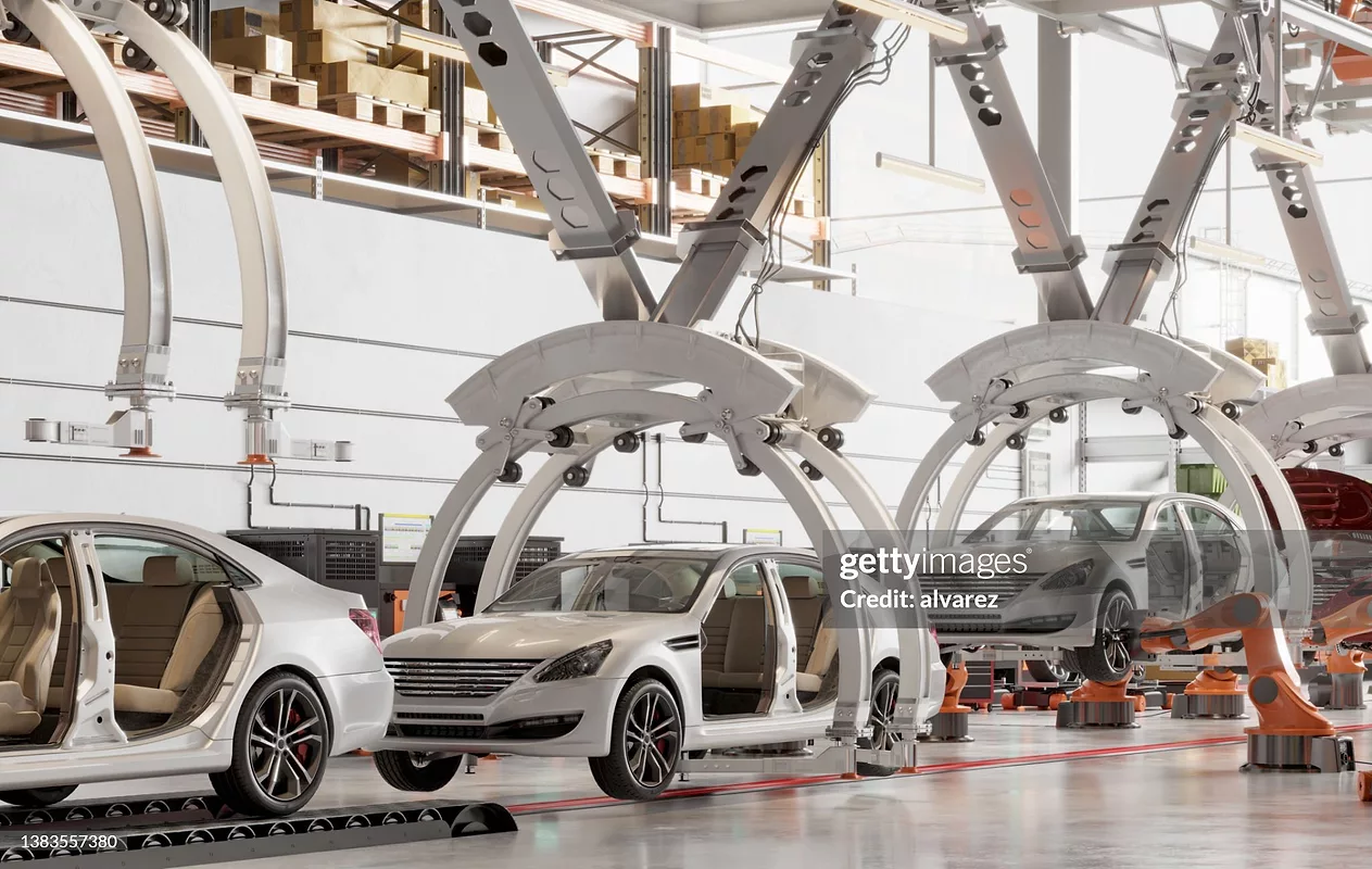 Automated automotive assembly line with robotic systems and vehicle bodies moving through a modern car manufacturing facility.