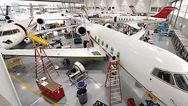 Aircraft maintenance hangar with multiple business jets undergoing inspection, repair, and maintenance, supported by technicians, tools, and service equipment.