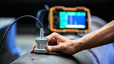 Ultrasonic Testing of a Metal Pipe Technician performing ultrasonic testing on a metal pipe with a handheld probe.