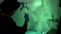 Fluorescent Penetrant Inspection of a Metal Component Technician performing fluorescent penetrant inspection on a metal component under UV light.