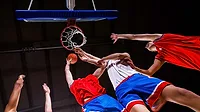 Basketball Players Competing for a Rebound Basketball players reaching for the ball beneath the hoop during a game.