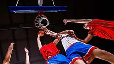 Basketball Players Competing for a Rebound Basketball players reaching for the ball beneath the hoop during a game.