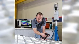 Technician measuring a metal assembly with a portable metrology system.
