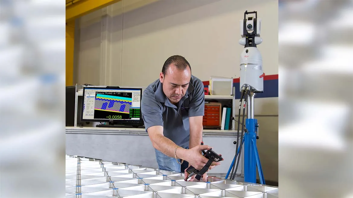 Technician measuring a metal assembly with a portable metrology system.