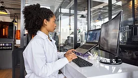 Medical engineer reviewing AI-assisted design software at a workstation.