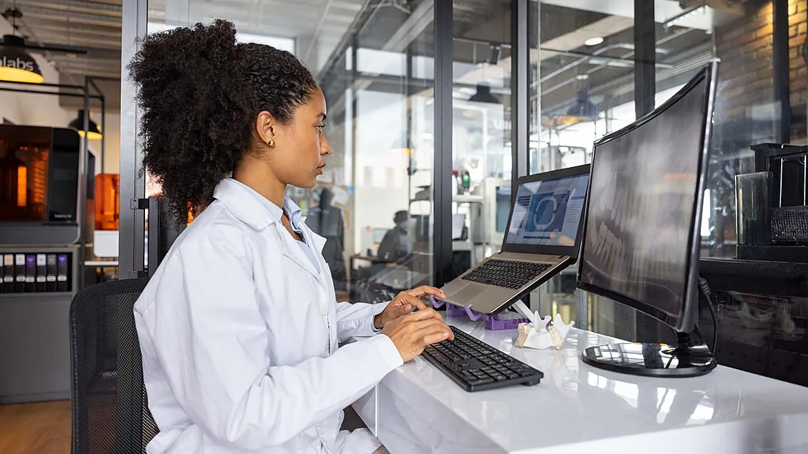 Medical engineer reviewing AI-assisted design software at a workstation.