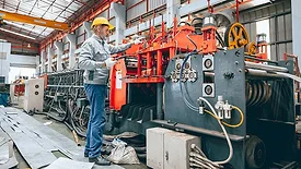 Manufacturing technician operating industrial machinery on a factory floor.