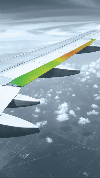 Graphics Aerospace, partial view of airplane wing with a view of landscape below and small puffs of clouds just below the wing.