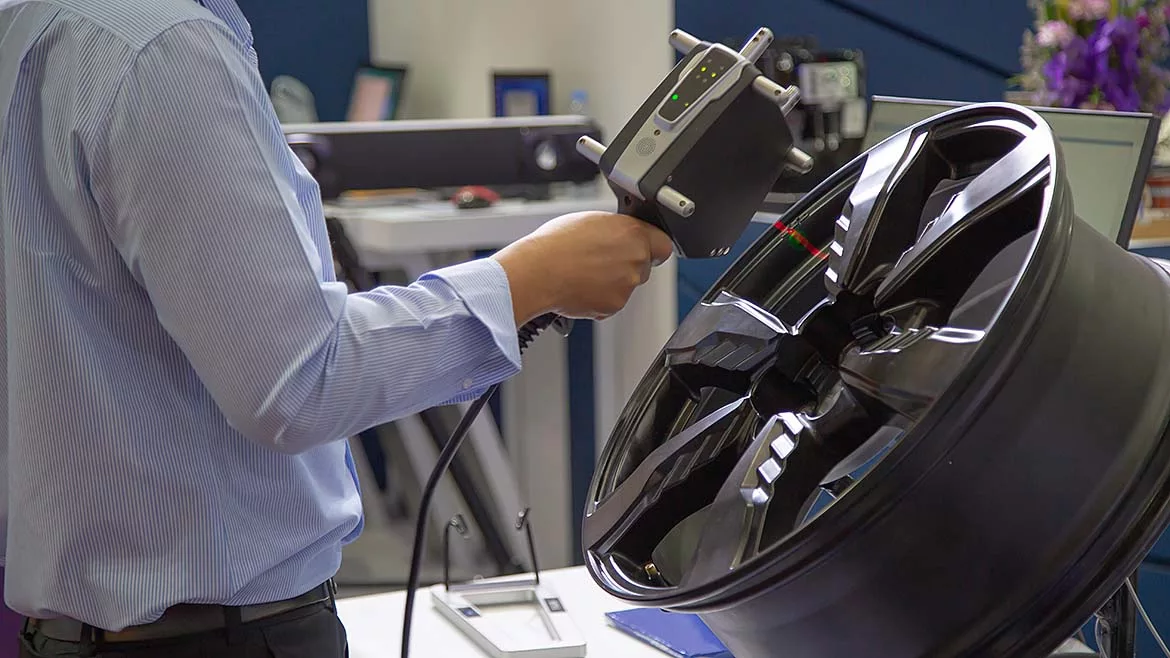 Handheld 3D scanner being used on a tire rim.