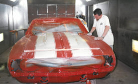 April 2024 Quality Infocenter FARO Kindig-it feature image of an car being painted in red with two wide white stripes on the front hood.