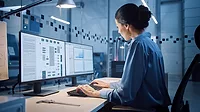 Factory Office: Female industrial engineer working on computer, on the computer screen, an industrial electronics design software.