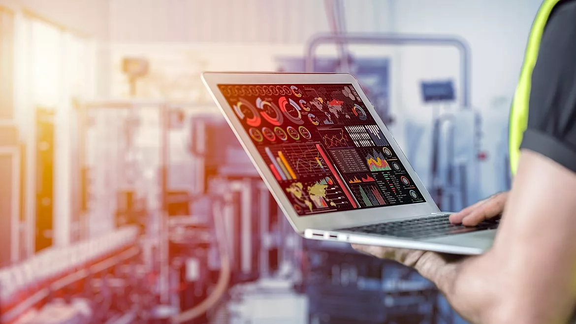 Closeup engineer using laptop computer to monitor and checking business data with blur factory background