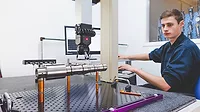 0524 Minitab InfoCenter Topic 2 Editorial Coordinate Measuring Machine Coordinate measuring machine (CMM) . The device is being programmed by a young male to measure the physical geometrical characteristics of an object. The operator is concentrating on the procedure. A display screen is seen in the background.