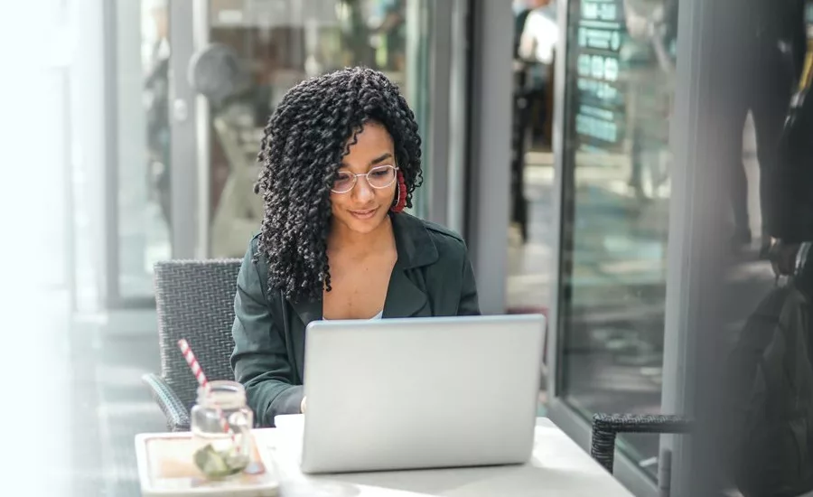 March 2024 Minitab feature image of young black female with laptop sitting outside.