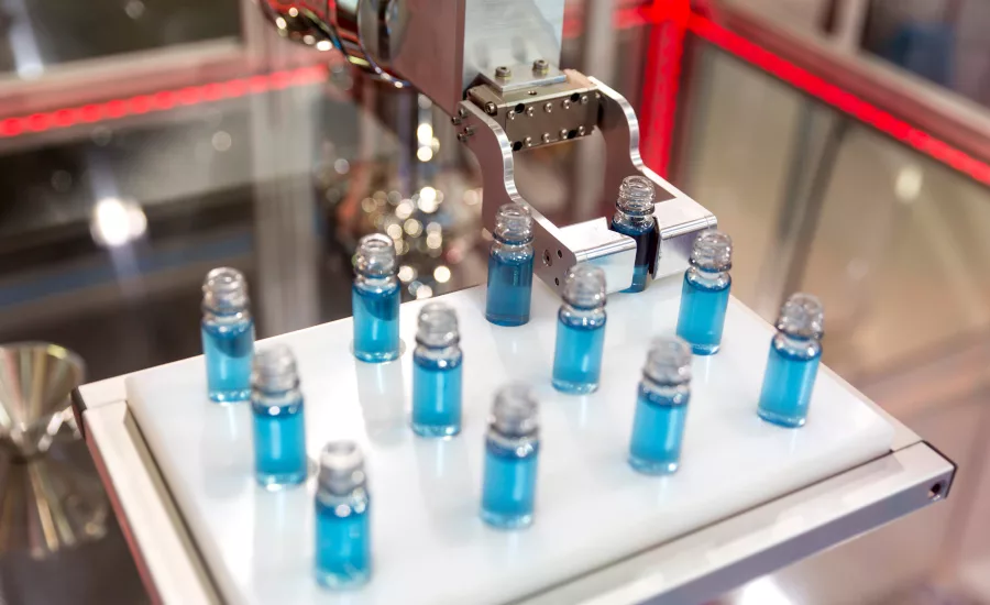 Robotic mechanical arm is manipulating chemical tubes full with blue substance in a medical laboratory during a test.