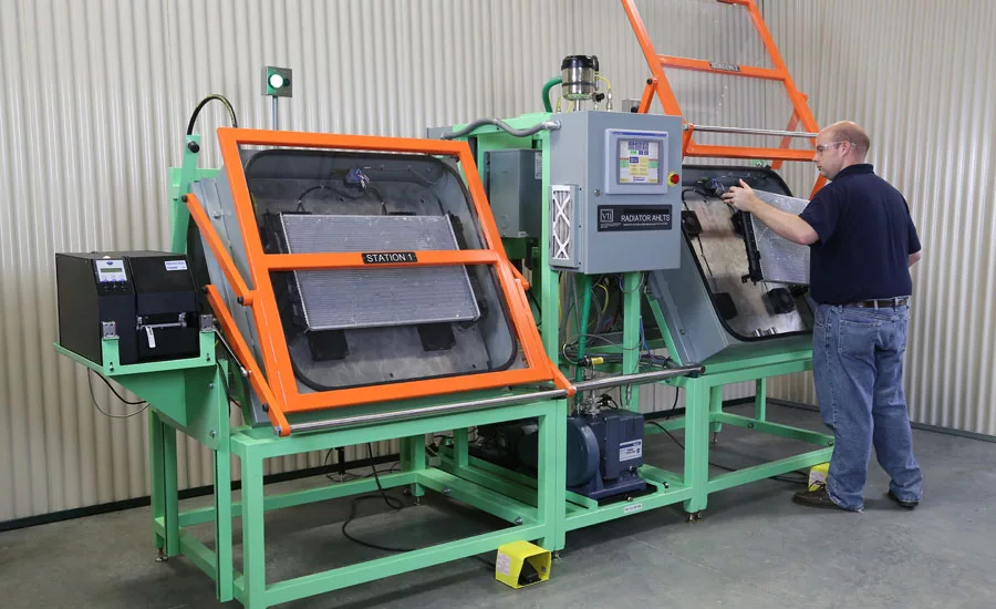 A technician loads a radiator into an atmospheric helium leak testing machine. Source: Inficon