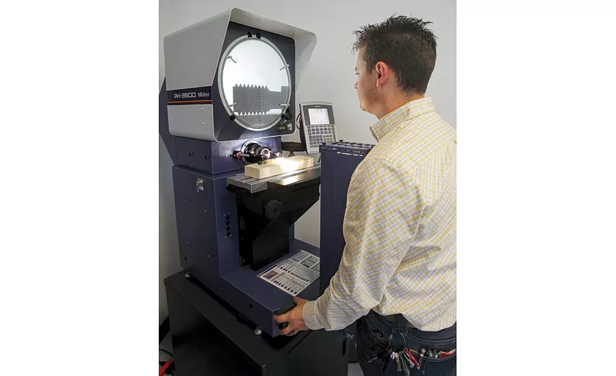 A metrology student inspects thread details of a go-no gage on the optical comparator.