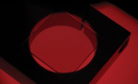 A calibration grid seated on a piece of tooling above a red backlight. 