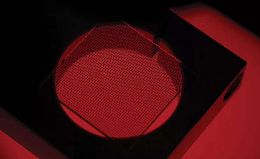 A calibration grid seated on a piece of tooling above a red backlight.