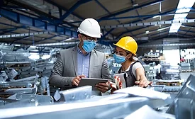 man and woman in factory setting with a tablet