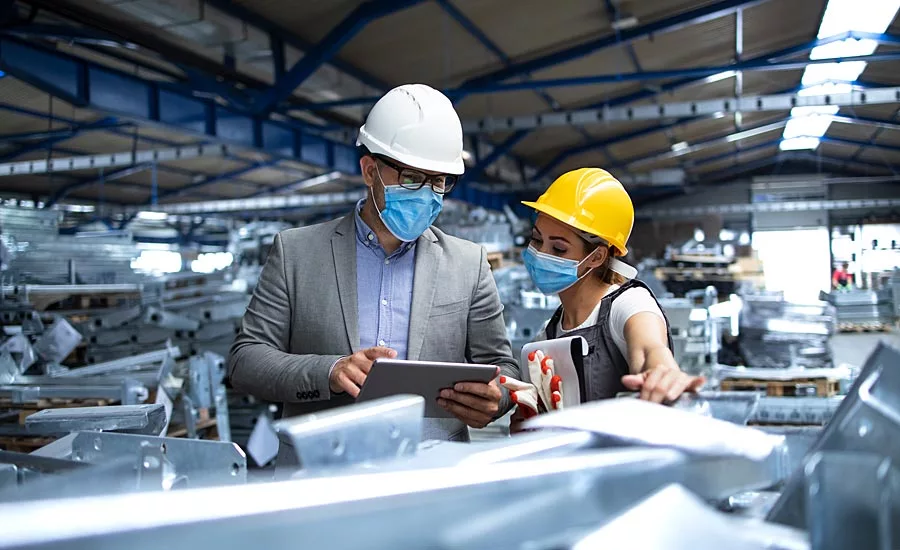 man and woman in factory setting with a tablet