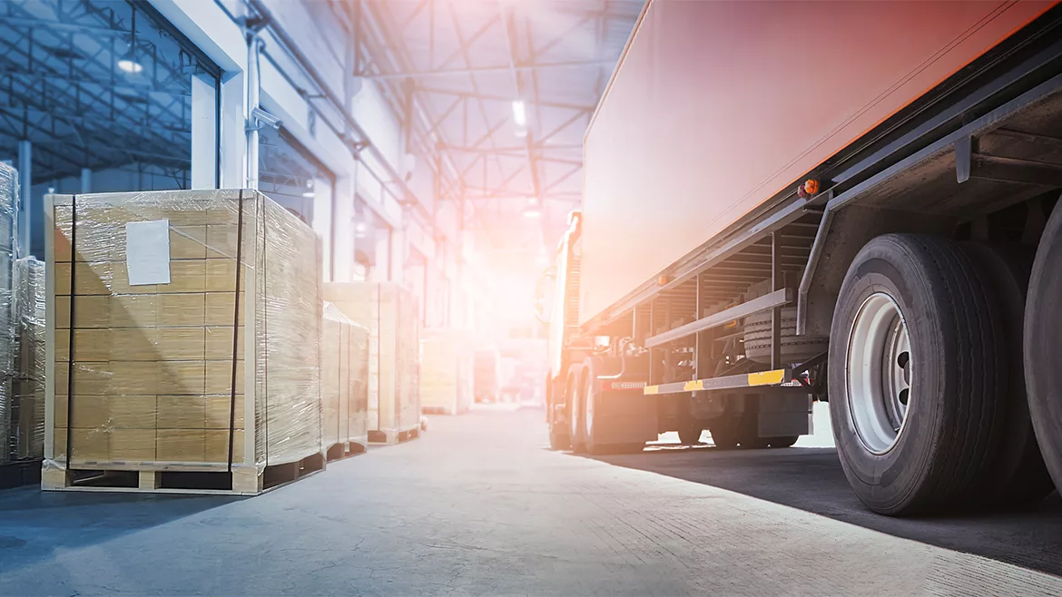 QM 1223 John Vandenbemden Column feature image of warehouse with pallets and a semi truck.