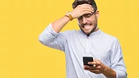 Young man texting using smartphone over isolated background stressed with hand on head.