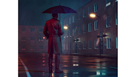 Man with umbrella and coat stands outside while it rains at night looking at a building.