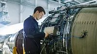 Aircraft Maintenance Mechanic Inspecting and Working on Airplane Jet Engine in Hangar 