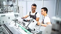 Young quality professionals Young quality professionals servicing modern industrial manufacturing machine in production factory.
