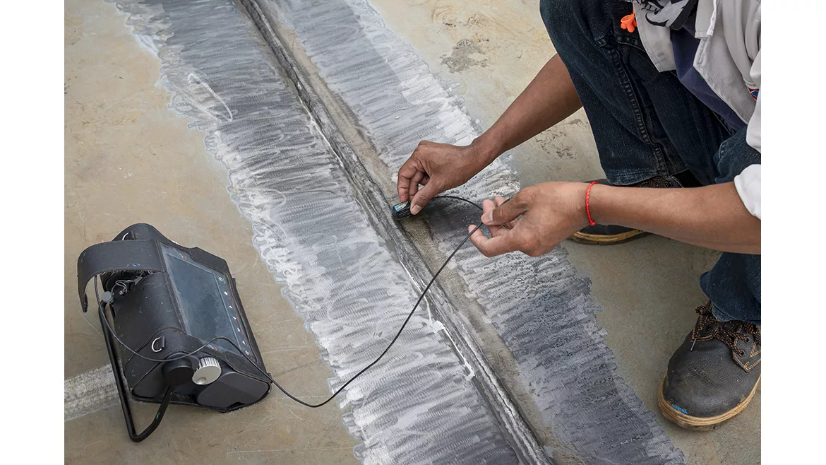 The inspectors are checking defect in welded of steel plate add joint with process Ultrasonic testing (UT) of Non-Destructive Testing(NDT) at industrial factory.