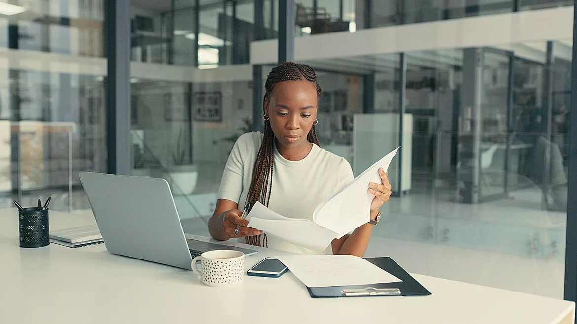 A young African American woman doing paperwork in a modern office.