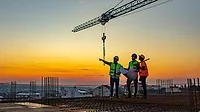Speaking of Quality column feature image three construction workers at construction site Speaking of Quality column feature image three construction workers at construction site with crane in the background.