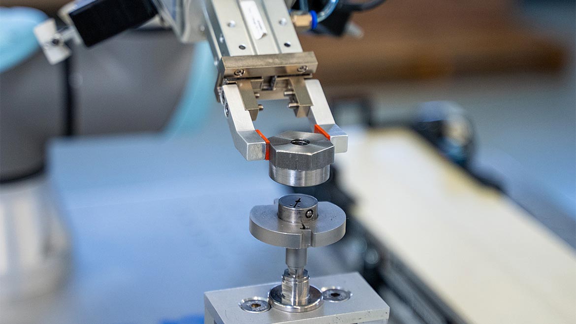 A collaborative robot presenting a part to a mechanical bore gage to measure the inside diameter of a machined part.