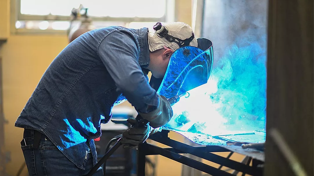 05 QM 0124 Lara Threet Column Industrial Technology Program. A student with a welding mask working on a project. 