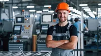 Young technician with orange hard hat is smiling and happy.