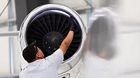 An airplane mechanic checking the jet engine while working on a private jet inside the hangar of a small general aviation airport in California.