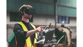 Male engineer working or using virtual reality headset for checking machinery in industry factory and wearing safety uniform and helmet.