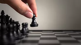 Hand of player moving a black pawn and a chess board