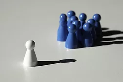 Leadership feature image of one white chess piece facing a group of blue chess pieces.